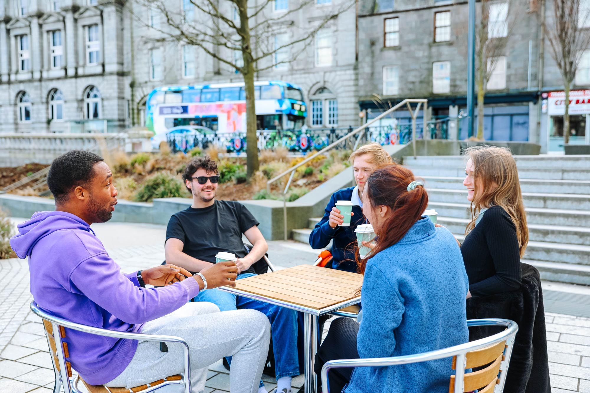 A group of students sharing a coffee in a local square close to their bauhaus student accommodation